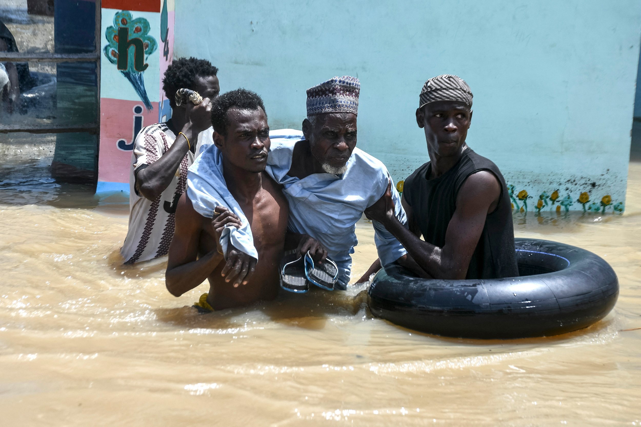 People help an elderly man wade through flood water on Sept. 12 in Maiduguri, Nigeria. Credit: Audu Marte/AFP via Getty Images